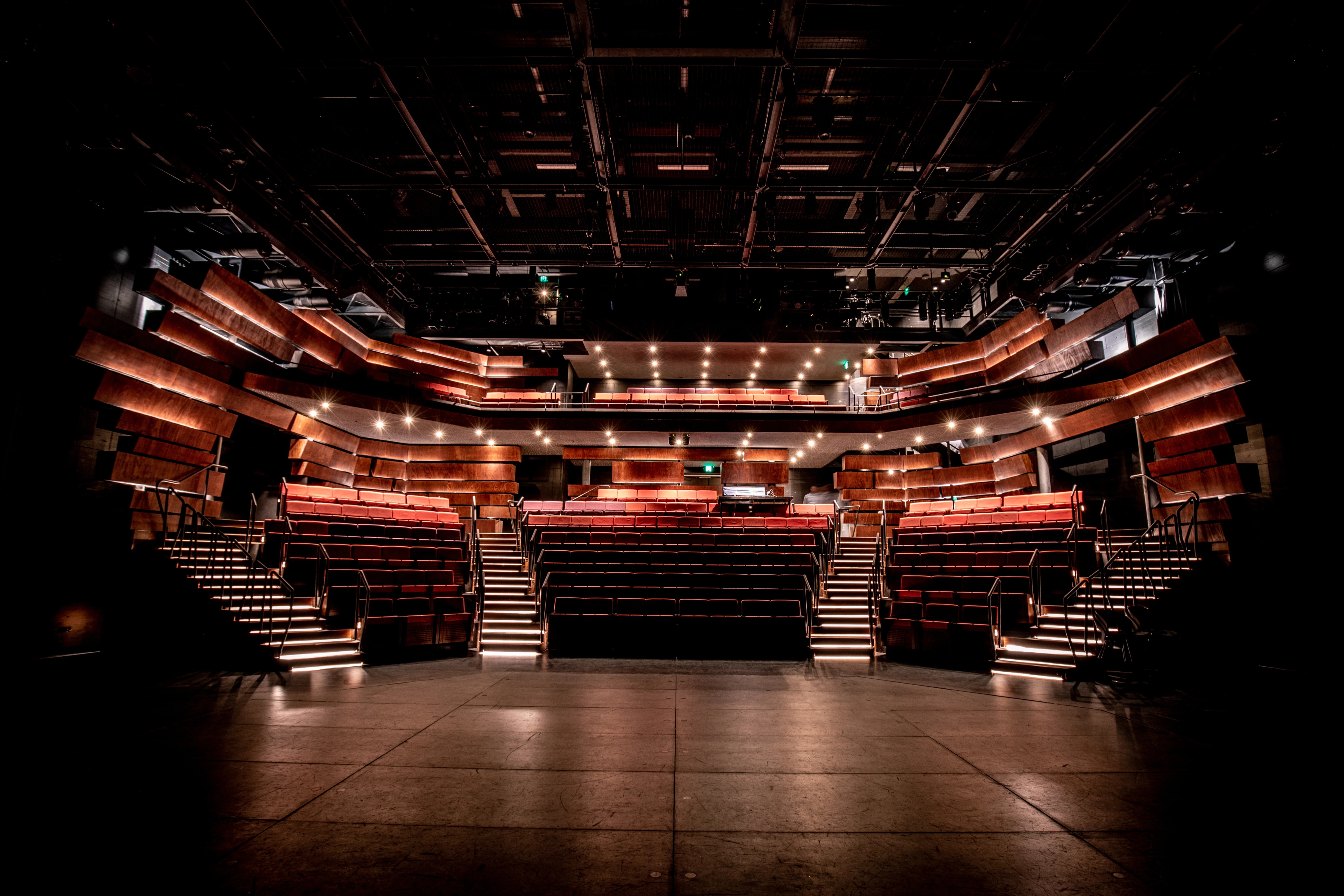 Inside a dark theatre with multiple layers of seating.